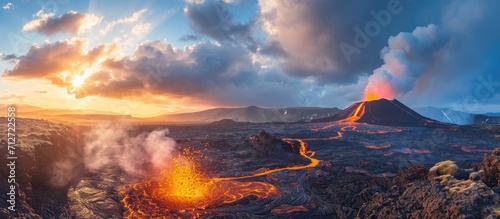 Daytime volcanic eruption on Reykjanes peninsula with lava shooting from Fagradalsfjall volcano crater in Icelandic Geopark, accompanied by clouds and steam in the sky. photo