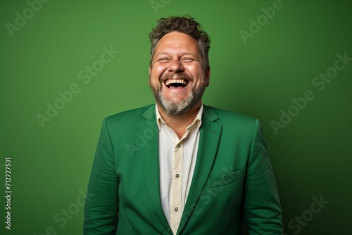 Portrait of a happy senior man laughing against a green background. © Inigo