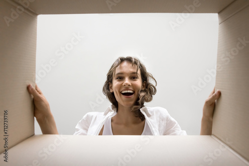 Obraz na plátně Excited happy young woman looking inside cardboard box with surprise, joy, amaze