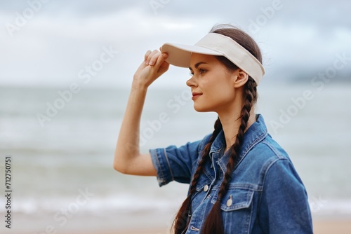 Joyful Summer Escape: A Beautiful Young Woman Enjoying the Sun and Sea in a Casual Fashion Dress, Hat, and Sunglasses, Standing on a White Sandy Beach with Blue Ocean and Sunny Sky in the Background. © SHOTPRIME STUDIO