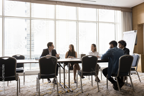 Diverse professional team of young business colleagues brainstorming on work project in boardroom. Multiethnic business partners discussing cooperation, partnership on meeting. Full length