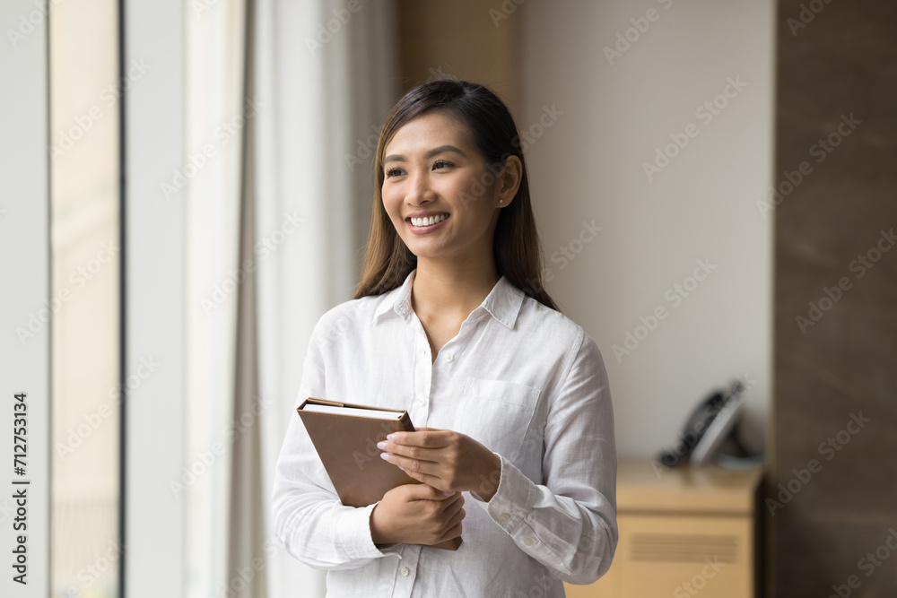Cheerful confident beautiful Asian businesswoman in formal shirt posing in office, looking at window away, smiling, laughing. Happy dreamy female business professional casual portrait Cheerful confident beautiful Asian businesswoman in formal shirt posing in office, looking at window away, smiling, laughing. Happy dreamy female business professional casual portrait