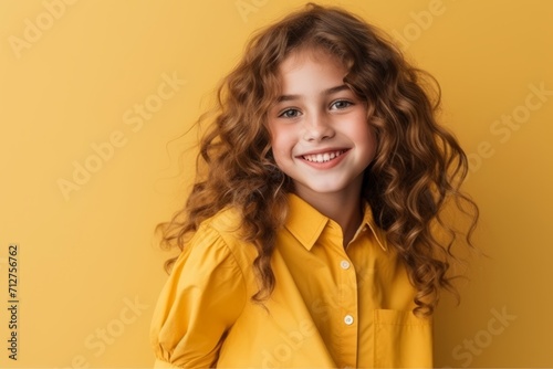 Portrait of a cute little girl with curly hair over yellow background