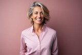 Portrait of a happy senior business woman smiling against a pink background