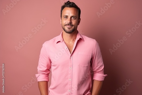 Portrait of a handsome young man in a pink shirt. Studio shot.