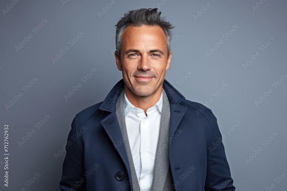 Portrait of handsome middle-aged man looking at camera while standing against grey background Portrait of handsome middle-aged man looking at camera while standing against grey background