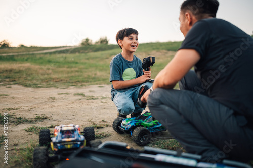 Boy talking to his father during playtime with two remote controlled car toys