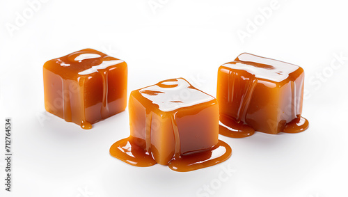 Sweet caramel candy cubes topped with caramel sauce on white background.