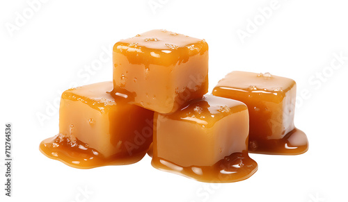 Sweet caramel candy cubes topped with caramel sauce on white background.