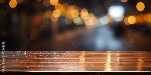 Blurred night car parking with bokeh background at coffee shop in raining day, featuring a wooden bar and an empty brown table for product montage with copy space.