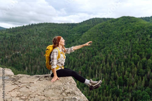 Young woman with backpack on mountain peak looking in beautiful mountain. Landscape with sporty young woman, green hills. Hiking. Nature. Travel and tourism.