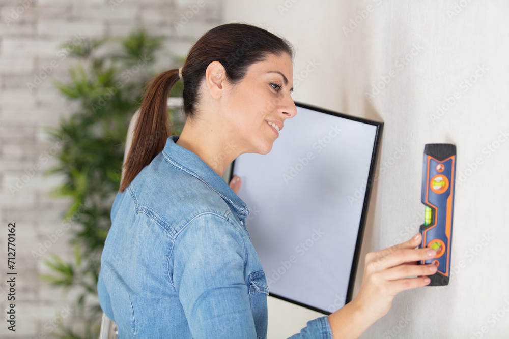 woman testing wall with spirit level to hang a picture woman testing wall with spirit level to hang a picture
