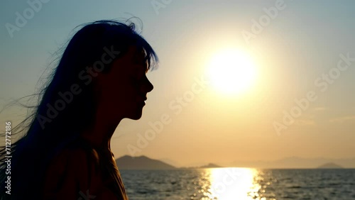 Silhouette of a girl at sea sunset in the wind. A hopefull girl silhouette enjoy the evening sea against colorful sky in summer. photo