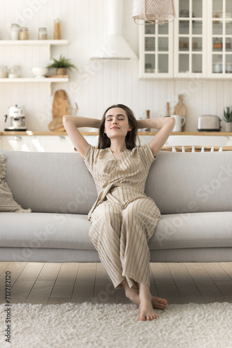 Peaceful woman rest on cozy sofa in living room with eyes closed, take deep breath fresh air, meditate, enjoy peace, no-stress, carefree single girl relaxing at home, fall asleep on couch at daytime