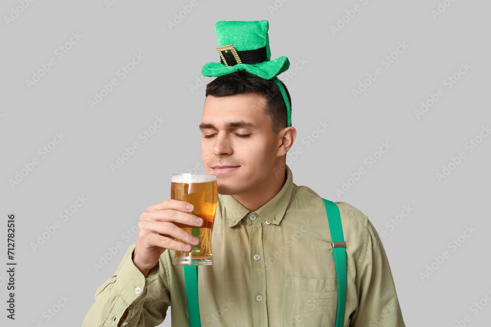 Happy young man with glass of beer on light background. St. Patrick's Day