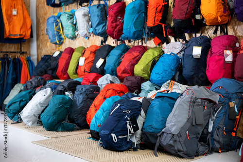 On wall and floor there is showcase with backpack for travelers and tourists - for climbing and hiking, waterproof clothes photo