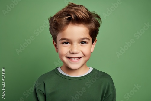 Portrait of a cute little boy looking at camera and smiling, over green background