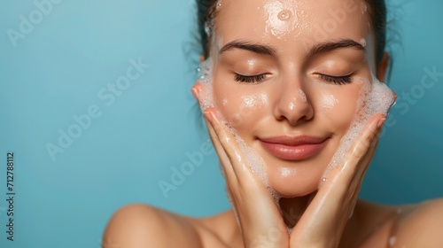 Portrait of a young beautiful woman wash her face with cleansing face foam. Skincare spa relax concept.