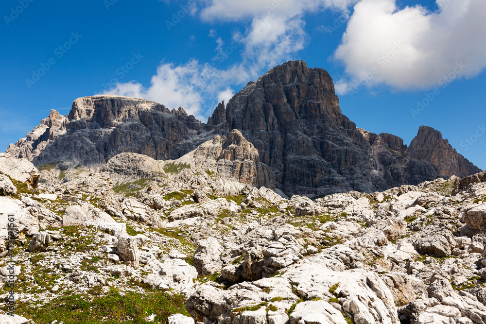 Bright rocks and mountain peaks are illuminated by bright daytime summer sun in Dolomites.