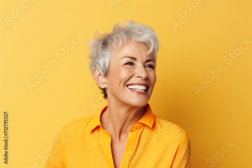 Portrait of smiling senior woman looking at camera isolated over yellow background
