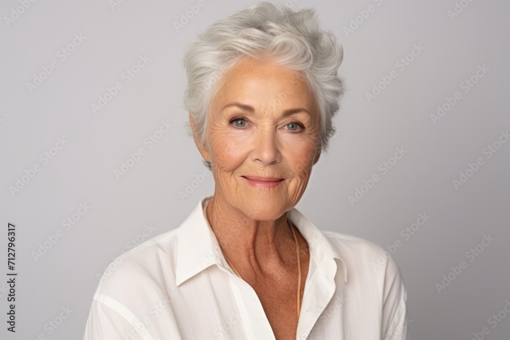 Portrait of a beautiful senior woman smiling at the camera against grey background