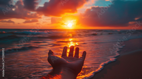 hand reaching out to a sunset at the beach 