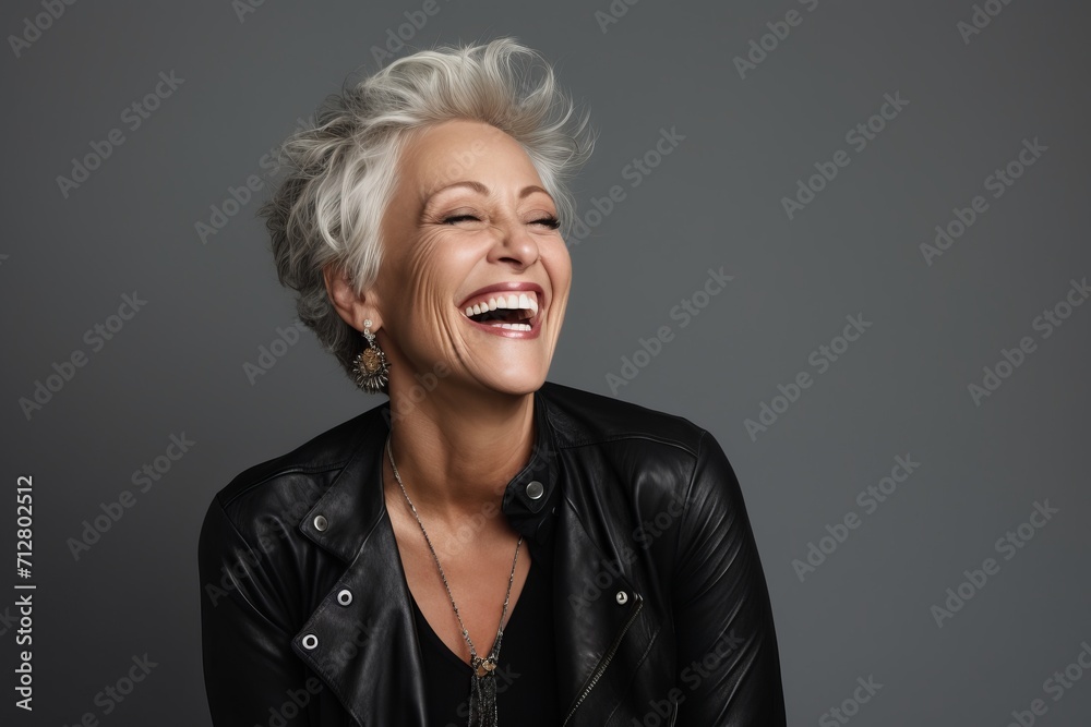 Laughing senior woman in leather jacket, isolated on grey background Laughing senior woman in leather jacket, isolated on grey background