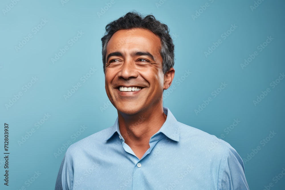 Portrait of a happy Indian man smiling at camera against blue background Portrait of a happy Indian man smiling at camera against blue background