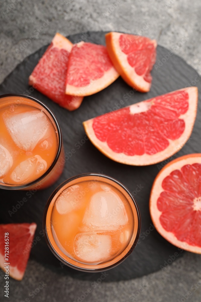 Tasty grapefruit drink with ice in glasses and fresh fruits on dark textured table, flat lay Tasty grapefruit drink with ice in glasses and fresh fruits on dark textured table, flat lay