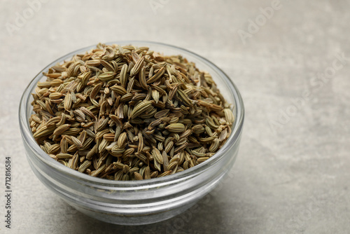 Fennel seeds in bowl on grey table, closeup. Space for text