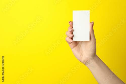 Woman holding blank business card on yellow background, closeup. Mockup for design photo