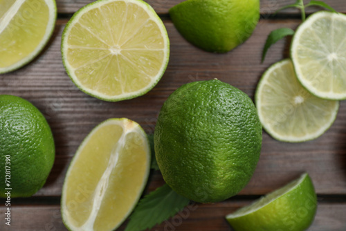 Flat lay composition with fresh limes and leaves on wooden table