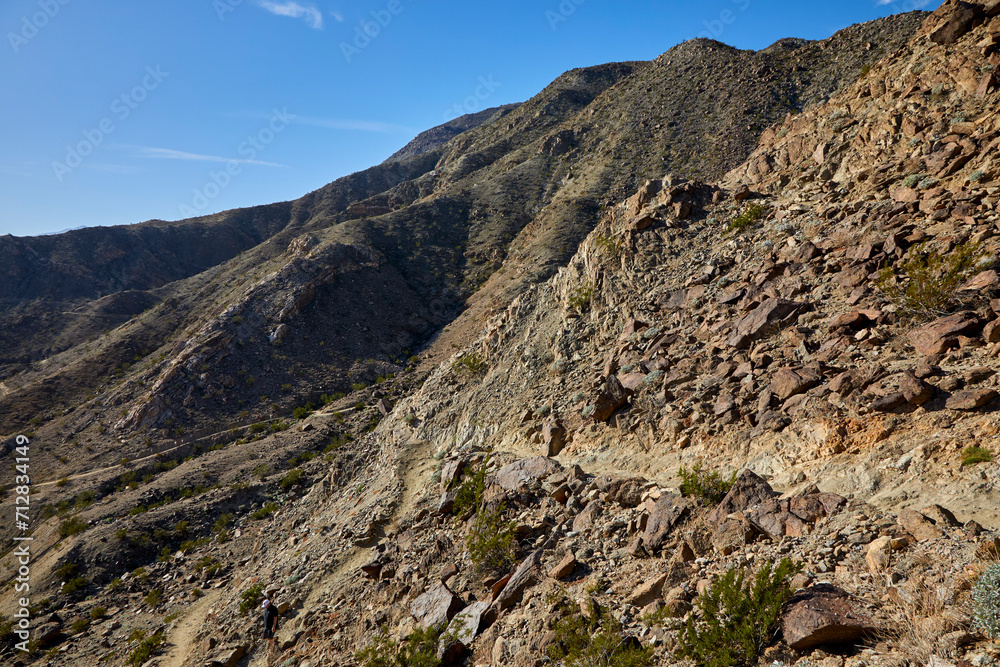 Hiking trail curving in the mountains near Palm Springs California with a blue sky and rustic landscape