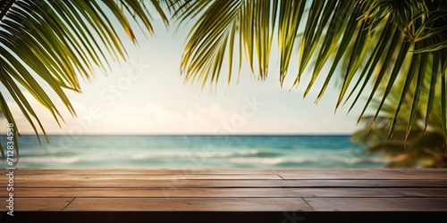 Tropical beach photo with green palm leaf and wooden table for product advertisement.