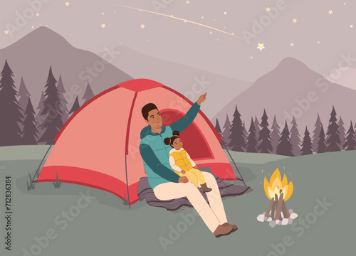 Smiling Black Father And His Little Daughter In Puffer Vest Sitting In Front Of Tent Looking Up At The Shooting Star. Full Length.