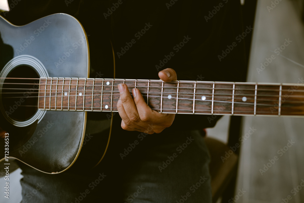 Fototapeta premium Photo detail of unknown person playing an old acoustic guitar. Concept of hobbies.