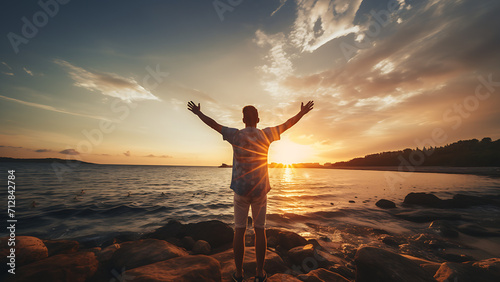 Young man's arms open at sunset enjoying freedom and life.