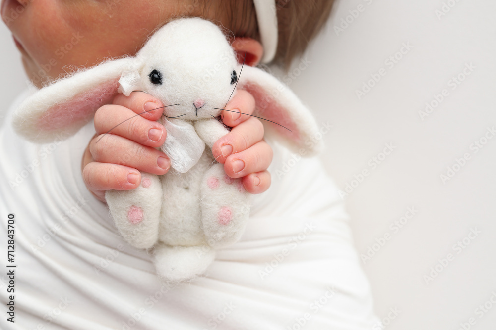 Sleep of a newborn in the first days of life. Portrait of a newborn one week old baby with a cute soft toy plush rabbit on a white background. Cute little fingers and hands of a child. Sleep of a newborn in the first days of life. Portrait of a newborn one week old baby with a cute soft toy plush rabbit on a white background. Cute little fingers and hands of a child.