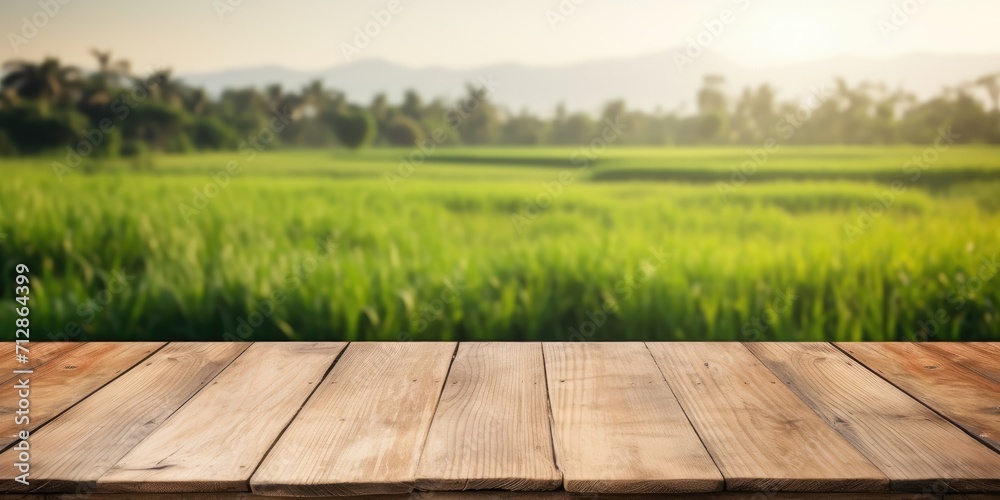 Empty wooden table with blurred morning paddy field in background for product display advertisement mock-up. Empty wooden table with blurred morning paddy field in background for product display advertisement mock-up.