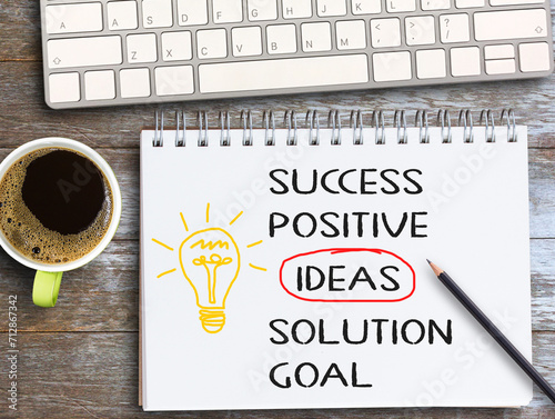 Top view text with success,positive,ideas,solution,goal on notebook with pencil,keybroad and coffee on wood table background photo
