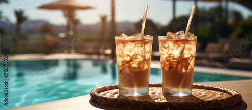 Two glasses of iced coffee with straws on luxury resort poolside bar table, luxury poolside frappe photo