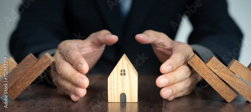 insurance with hands protect domino. Businessman hands stop dominoes falling in house crisis. business risk control and planning and strategies to run prevent insurance businesses. photo