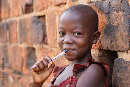 An 11-year-old Ugandan girl smiling, holding a pen.