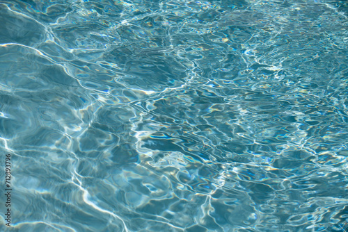Water background  ripple waves. Blue swiming pool pattern. Sea surface. Water in swimming pool with sun reflection. Banner with copy space.