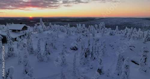 Aerial tracking tilt shot of a house and snow covered wilderness, sunset in Lapland photo