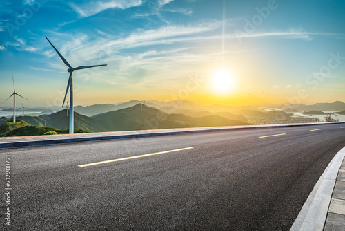 Asphalt highway and wind turbines with mountain natural landscape at sunset. High Angle view. photo