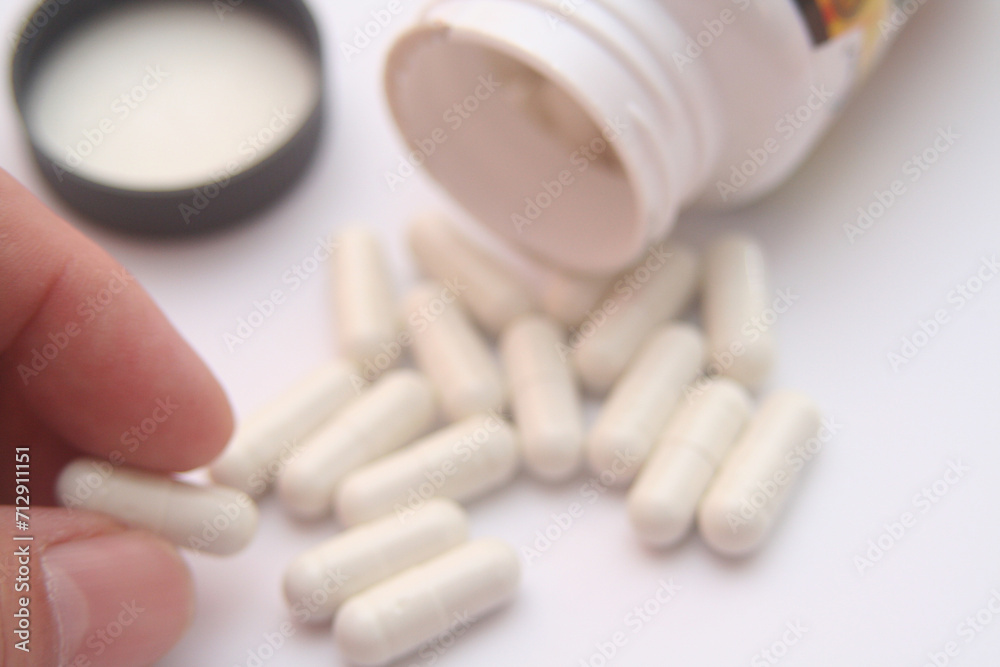 close up of hand holding white capsules on white background with copy space close up of hand holding white capsules on white background with copy space