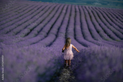 Lavender field girl. Back view happy girl in pink dress with flowing hair runs through a lilac field of lavender. Aromatherapy travel