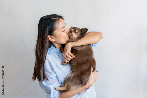 Joyful fit woman sitting having fun with cute dog on the armchair at living room one autumn day , friendship and love for pets.