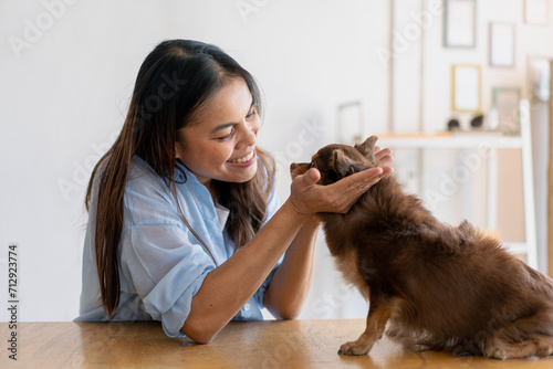 Joyful fit woman sitting having fun with cute dog on the armchair at living room one autumn day   friendship and love for pets.